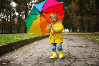 Photo of Little girl with colorful umbrella walking outdoors