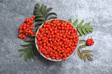 Photo of Fresh ripe rowan berries and leaves on grey table, flat lay