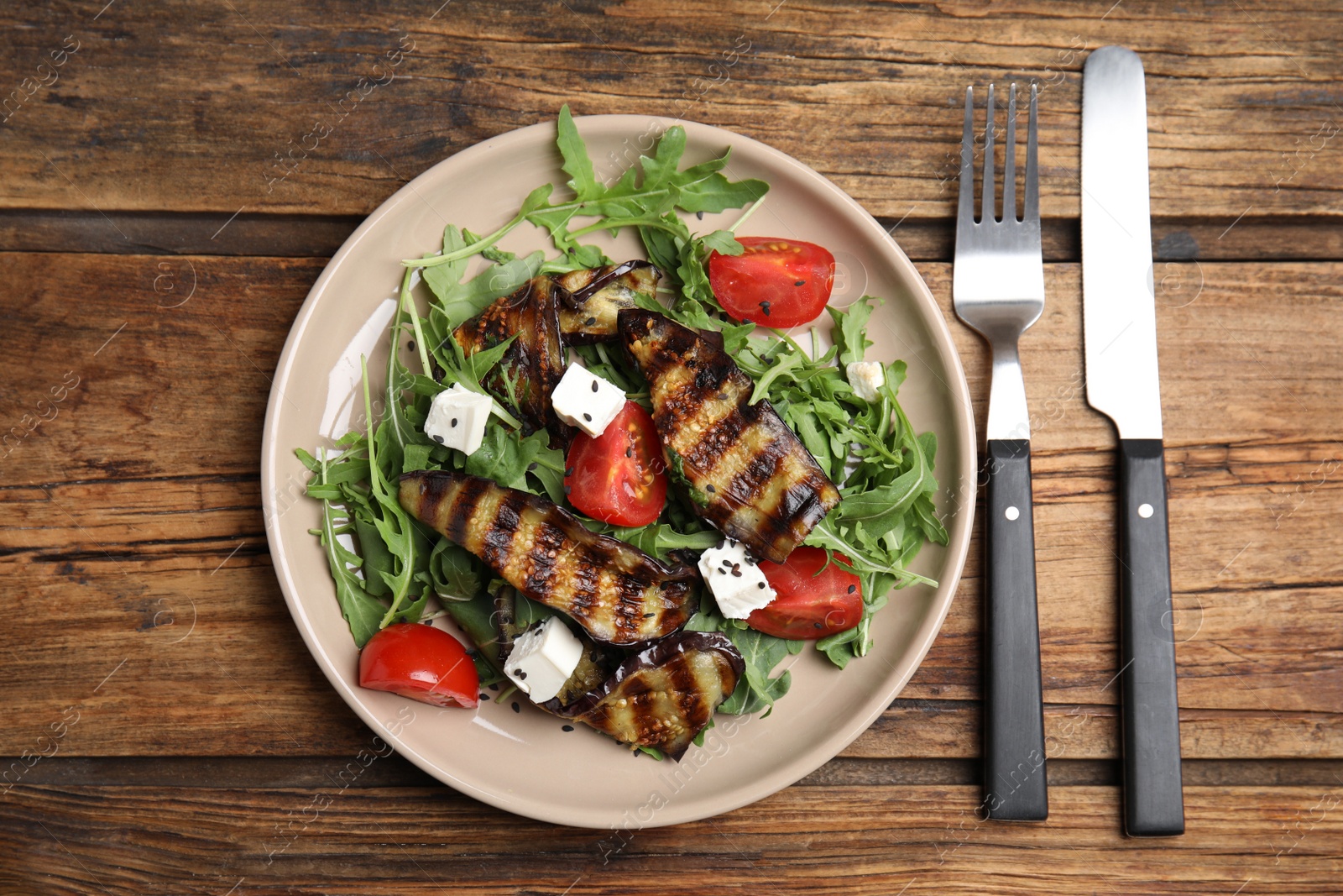 Photo of Delicious salad with roasted eggplant, feta cheese and arugula served on wooden table, flat lay