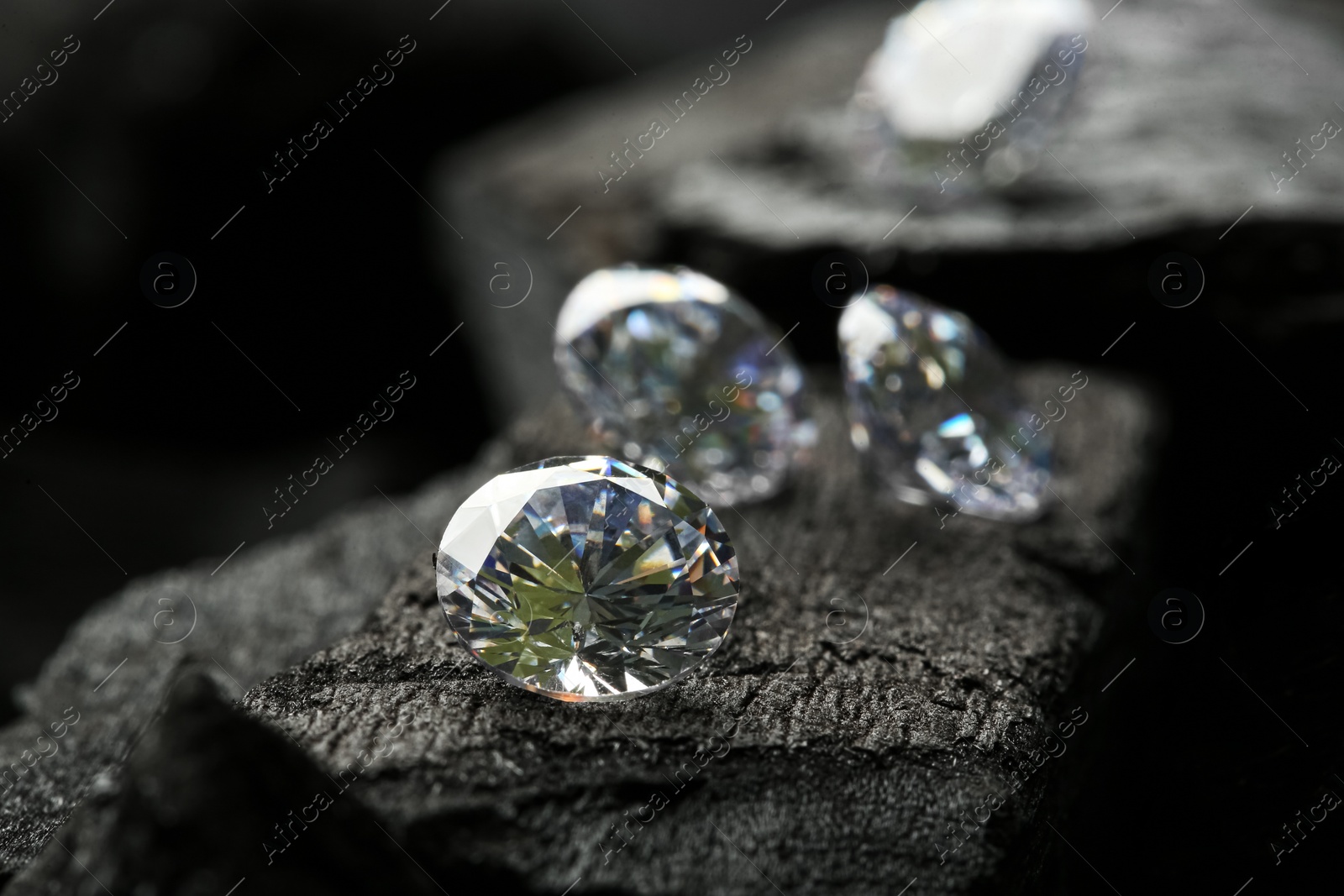 Photo of Beautiful shiny diamonds on coal, closeup view