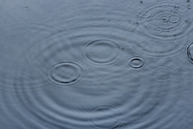 Photo of Rain drops falling down into puddle outdoors