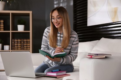 Photo of Young woman watching webinar on sofa at home