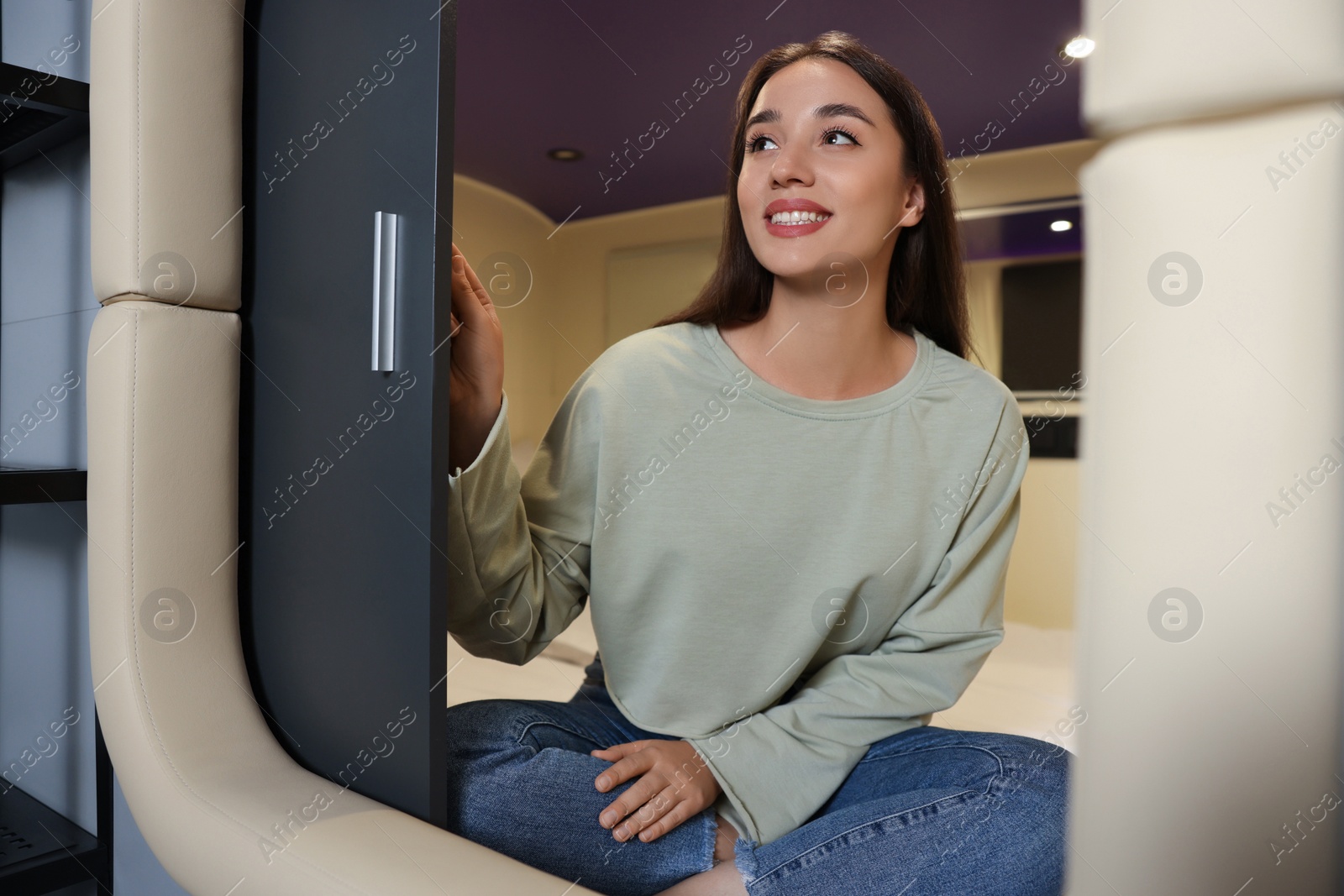 Photo of Happy young woman closing door of capsule in pod hostel