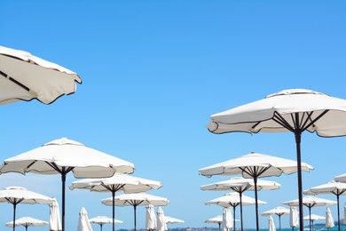 Photo of Beautiful white beach umbrellas against blue sky