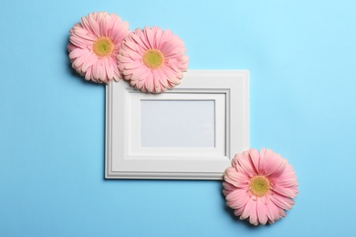 Photo of Empty photo frame and flowers on color background, top view. Space for text