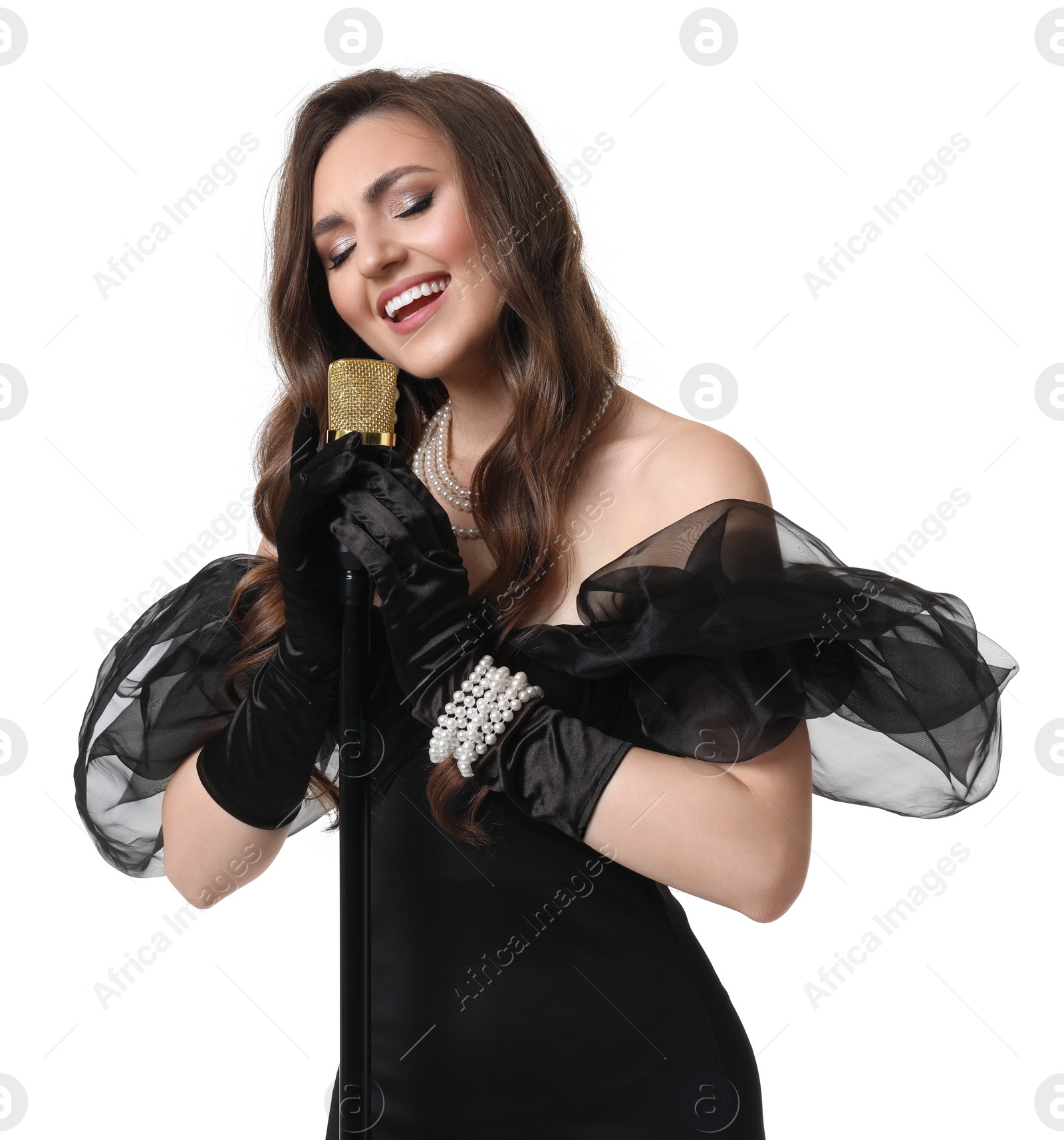 Photo of Beautiful young woman in stylish black dress with microphone singing on white background