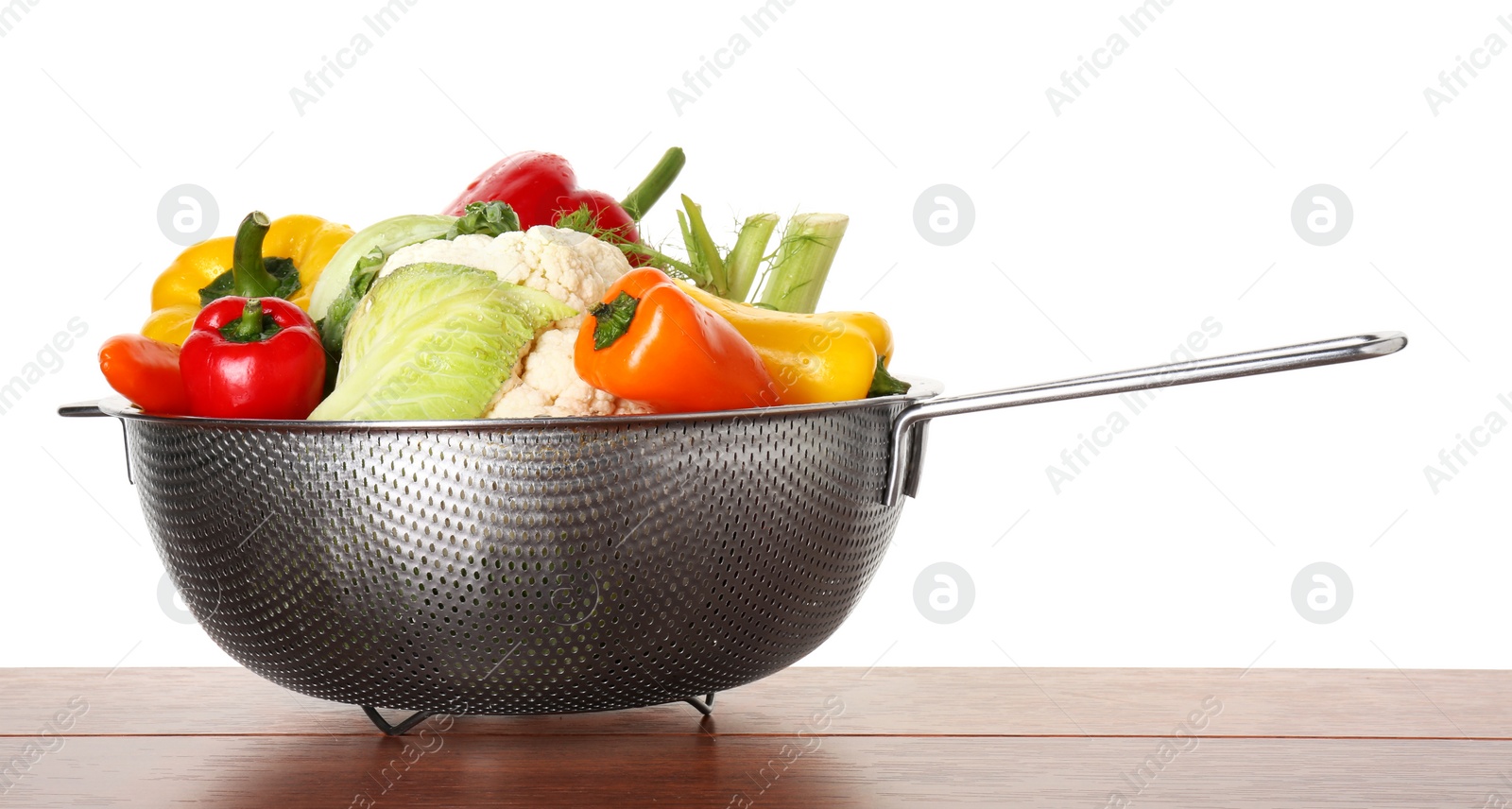 Photo of Metal colander with different vegetables on wooden table against white background