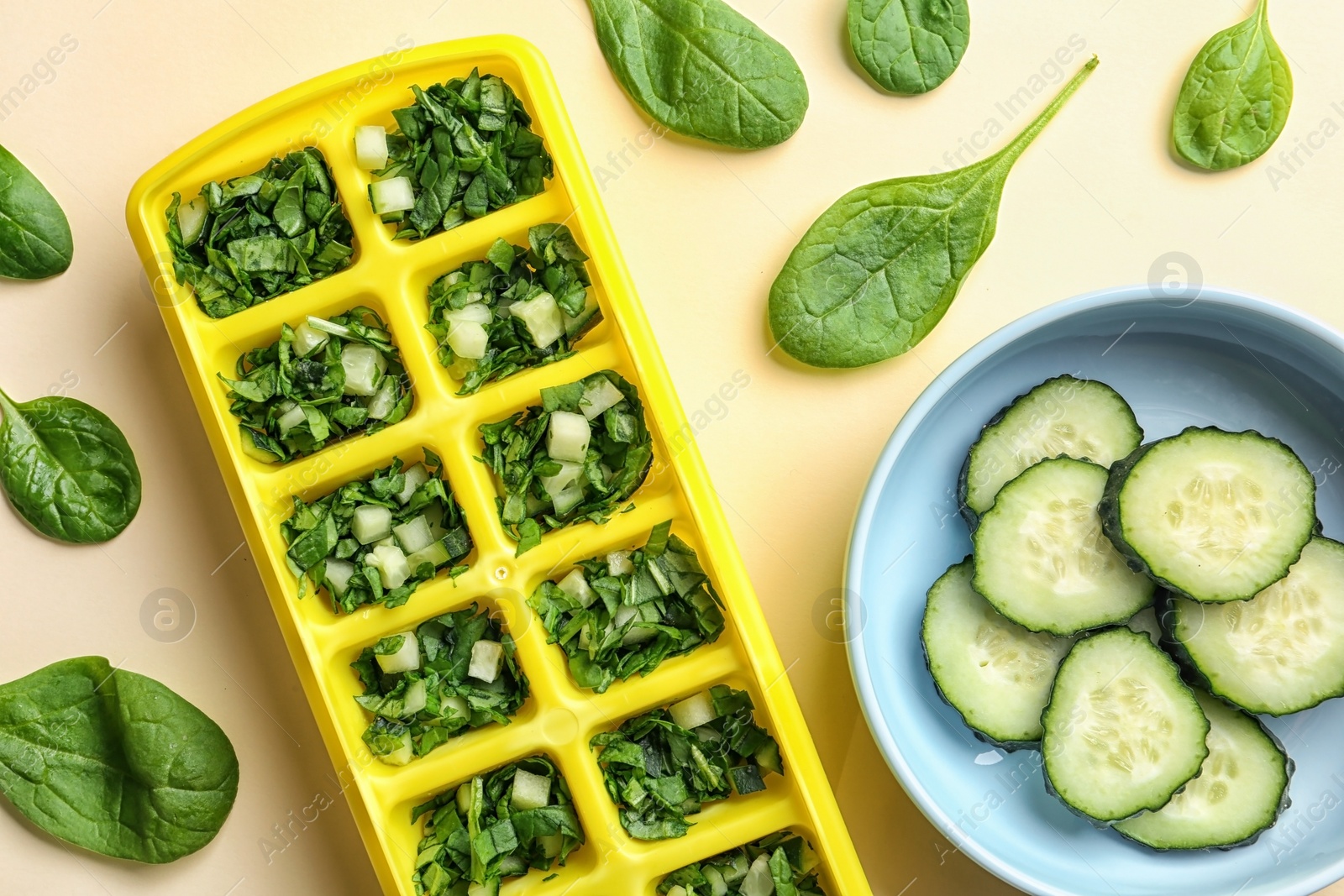 Photo of Flat lay composition with ice cube tray, fresh spinach and cucumber on color background