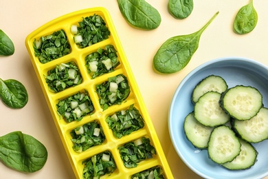 Photo of Flat lay composition with ice cube tray, fresh spinach and cucumber on color background
