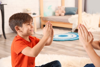 Hearing impaired mother and her child talking with help of sign language indoors