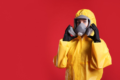 Woman wearing chemical protective suit on red background, space for text. Virus research