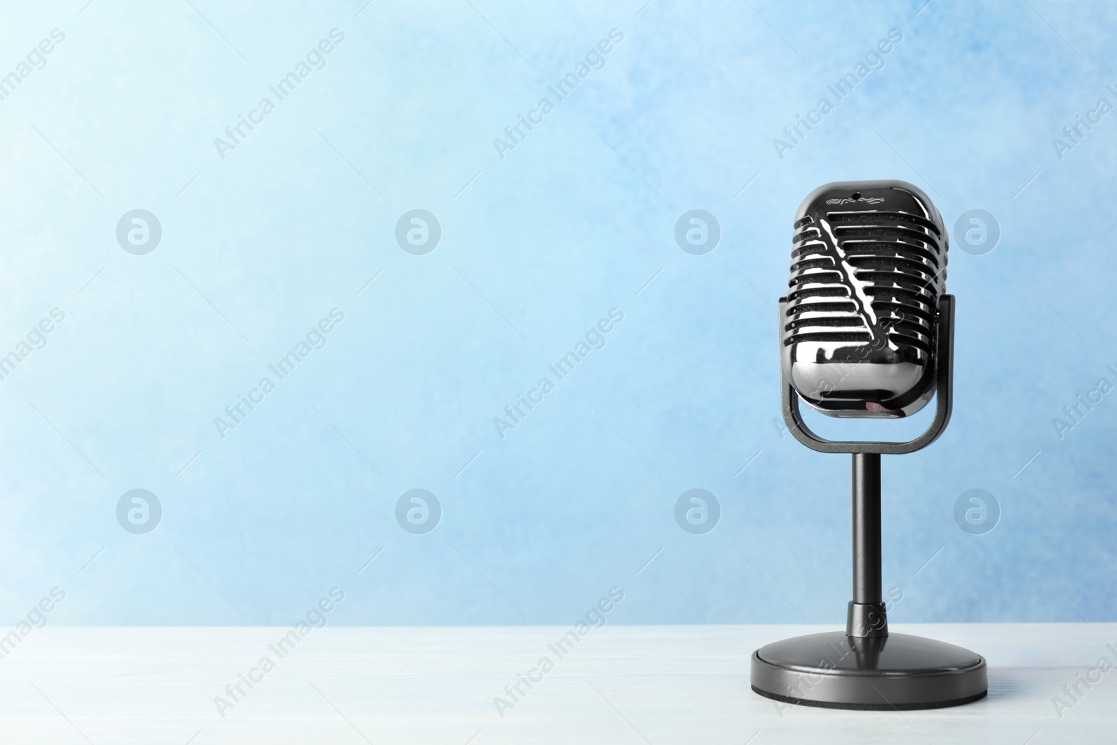 Photo of Retro microphone on table against color background. Space for text