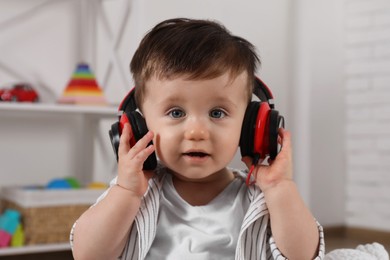 Cute little boy in headphones listening to music at home
