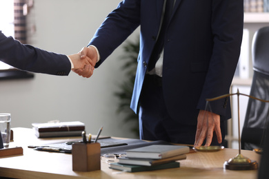 Photo of Male lawyer shaking hands with client in office, closeup