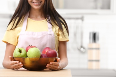 Photo of Woman with bowl of fresh apples at table in kitchen, closeup. Space for text