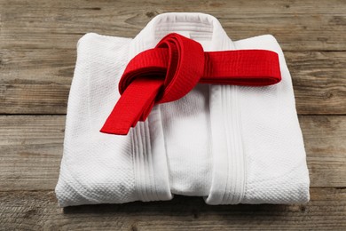 Red karate belt and white kimono on wooden background