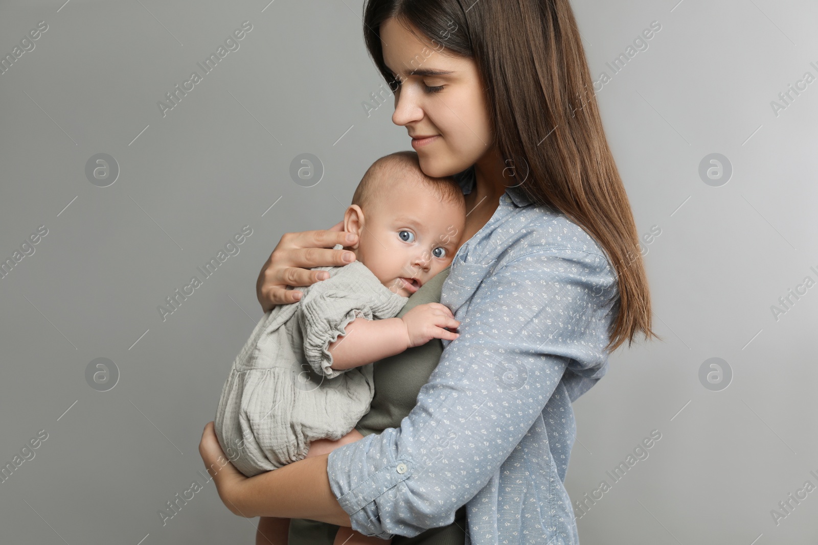 Photo of Beautiful mother with her cute baby on grey background