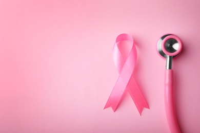 Photo of Pink ribbon and stethoscope on color background, top view with space for text. Breast cancer concept