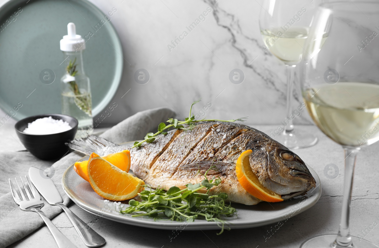 Photo of Seafood. Delicious baked fish served with orange and microgreens on light textured table