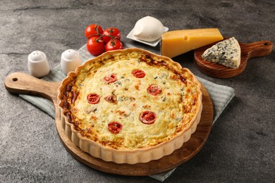 Photo of Delicious homemade cheese quiche and ingredients on gray table