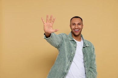 Man giving high five on beige background. Space for text