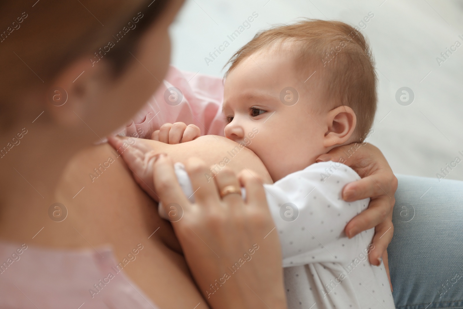 Photo of Young woman breastfeeding her baby at home, closeup