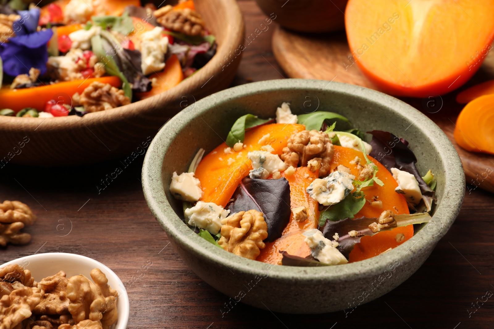 Photo of Delicious persimmon salad with cheese and pomegranate served on wooden table