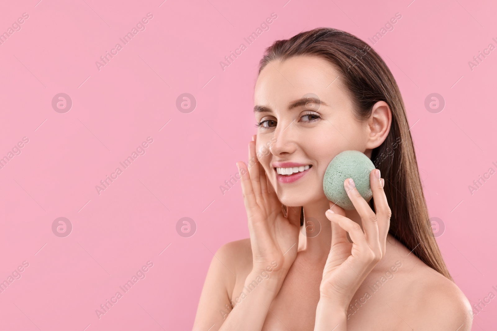 Photo of Happy young woman with face sponge on pink background. Space for text