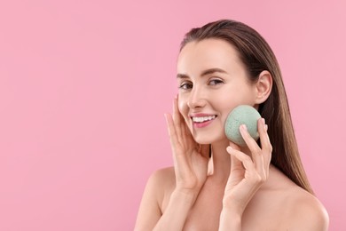 Happy young woman with face sponge on pink background. Space for text