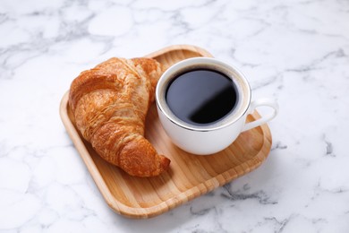 Photo of Tasty breakfast. Cup of coffee and fresh croissant on white marble table