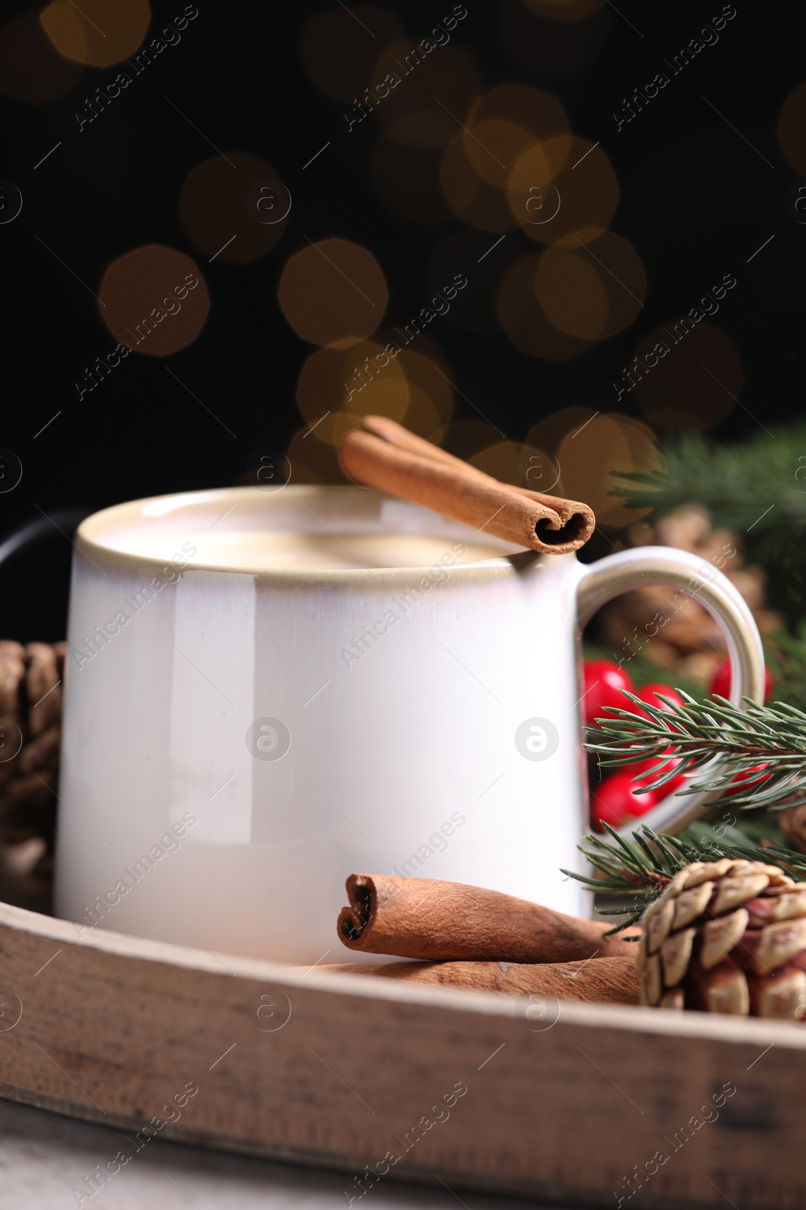 Photo of Tasty eggnog with cinnamon sticks on grey table, closeup