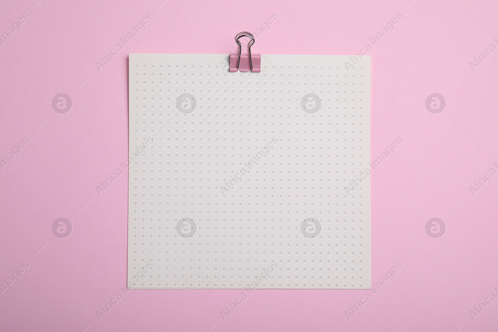 Photo of Sheet of paper with clip on pink background, top view