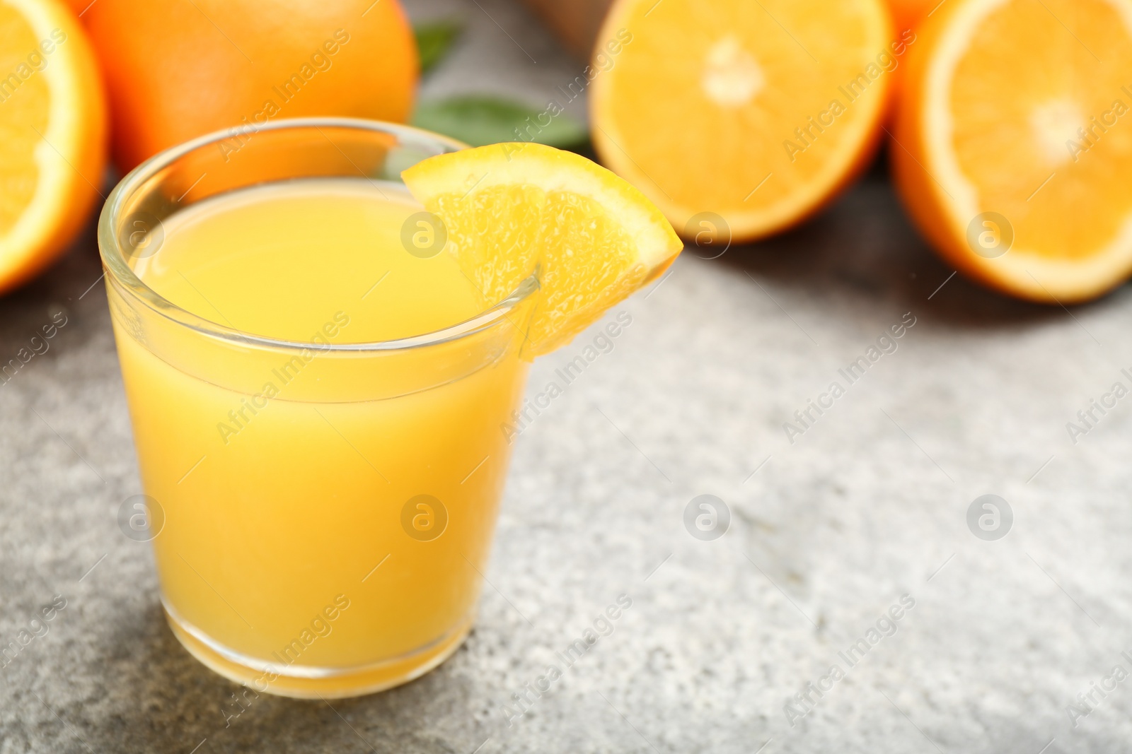 Photo of Delicious orange juice and fresh fruit on grey table, closeup. Space for text