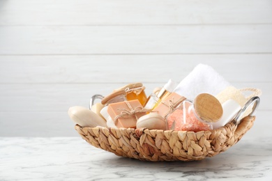 Photo of Basket with different soap bars and bath accessories on marble table. Space for text