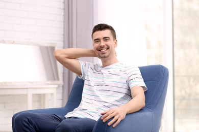 Photo of Young man sitting in armchair at home