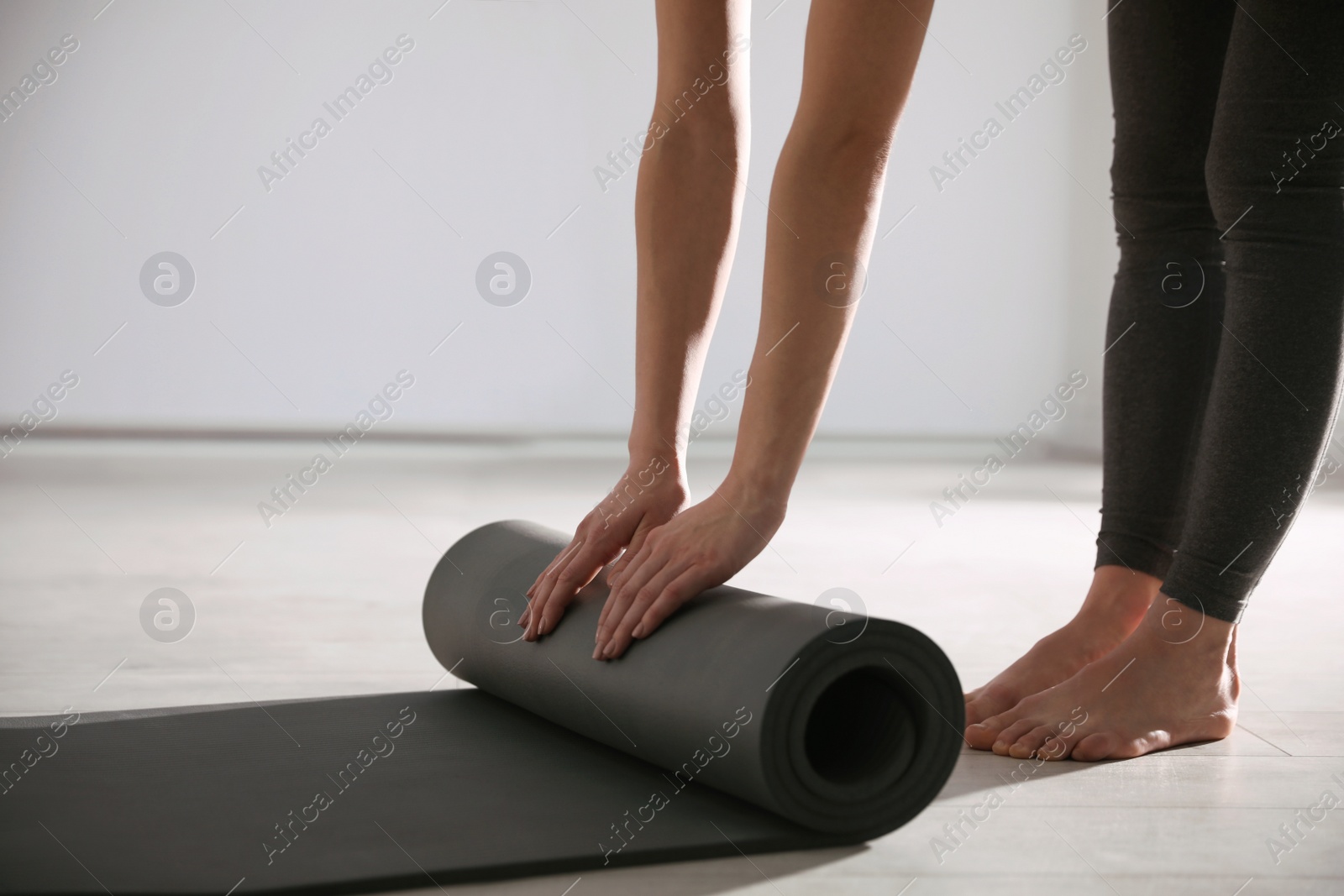 Photo of Woman rolling yoga mat in studio, closeup