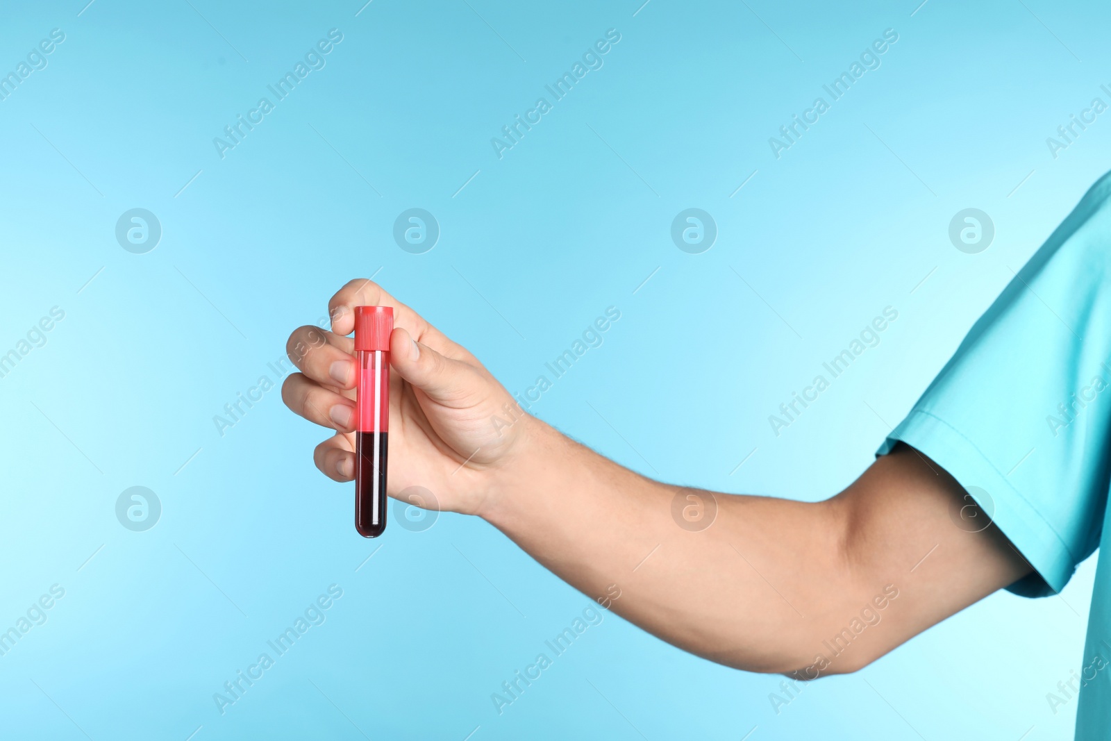 Photo of Male doctor holding test tube with blood sample on color background, closeup. Medical object