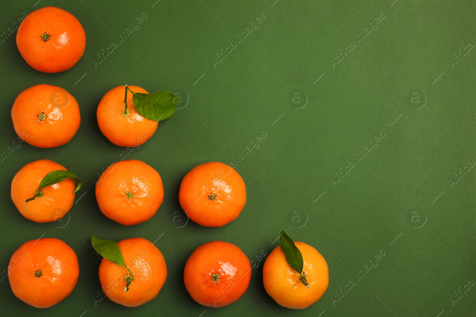 Photo of Delicious tangerines and leaves on green background, flat lay. Space for text