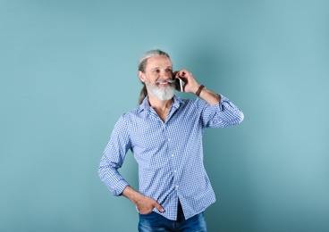Photo of Portrait of handsome mature man with mobile phone on color background