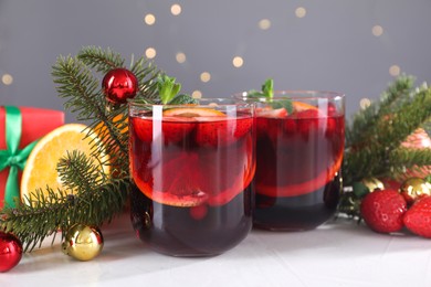 Aromatic Christmas Sangria in glasses and festive decor on white table, closeup