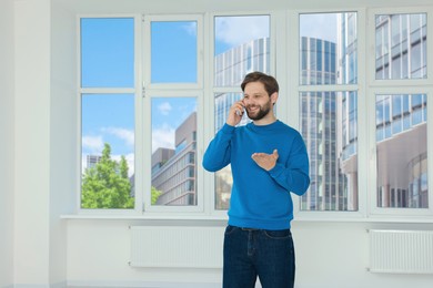 Photo of Man in casual clothes talking on phone indoors, space for text