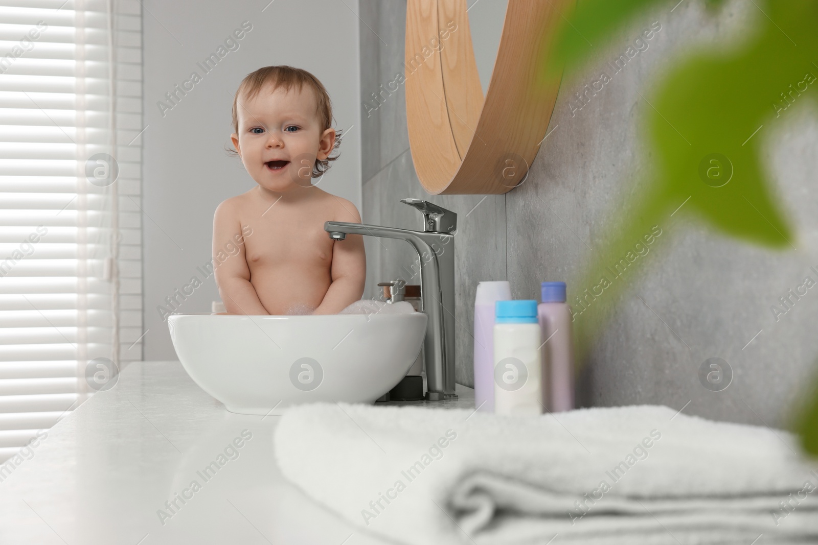 Photo of Cute little baby bathing in sink at home