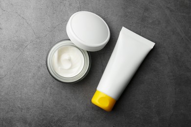 Photo of Jar and tube of face cream on grey table, flat lay