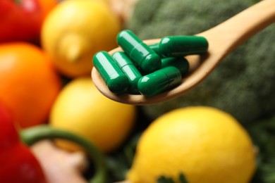 Photo of Dietary supplements. Spoon with pills over food products, closeup