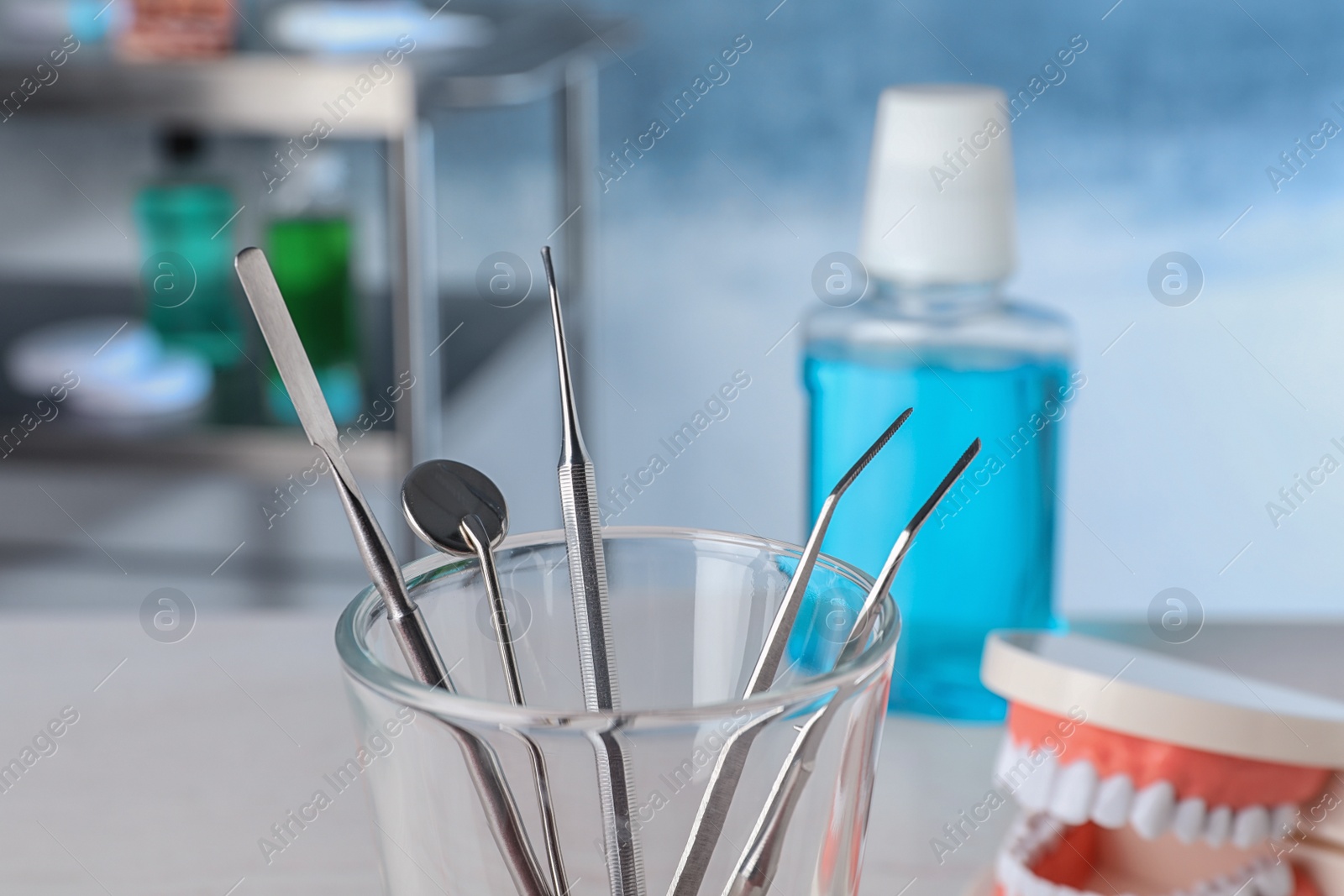 Photo of Glass with different dentist tools in lab, closeup