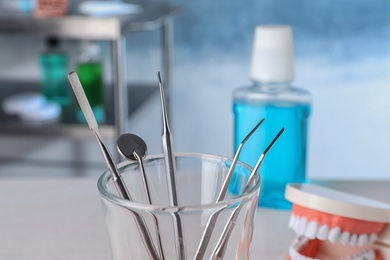 Photo of Glass with different dentist tools in lab, closeup
