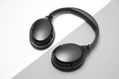 Photo of Modern black wireless headphones on color background
