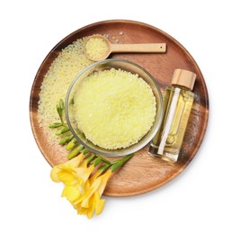 Photo of Yellow sea salt in bowl, flowers, cosmetic product and spoon isolated on white, top view