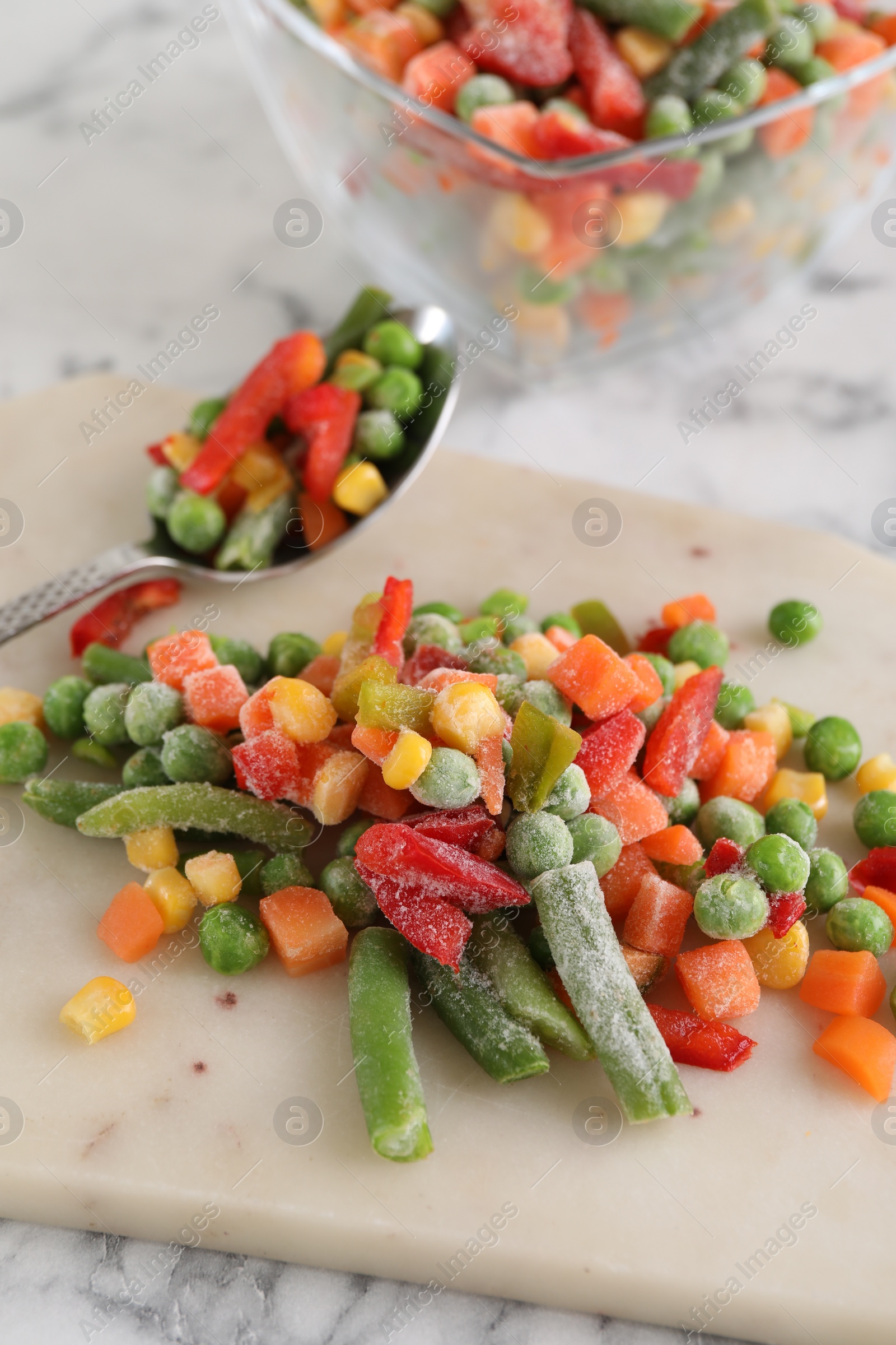 Photo of Mix of different frozen vegetables on white marble table, closeup