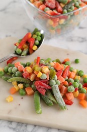 Photo of Mix of different frozen vegetables on white marble table, closeup